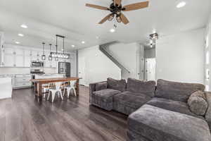 Living room featuring recessed lighting, a ceiling fan, dark wood-style floors, and stairs