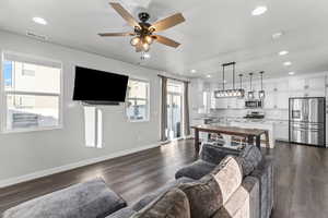 Living room featuring dark wood-style floors, recessed lighting, and a ceiling fan