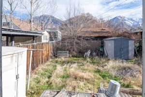 Fenced backyard featuring a tool shed and storage shed and a mountain view
