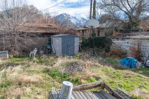 Fenced backyard featuring a tool shed and storage shed and a mountain view