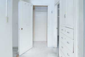 Hallway featuring built in linen closet and drawers and coat closet