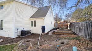 View of side of home with a shingled roof, a vegetable garden, and a fenced backyard