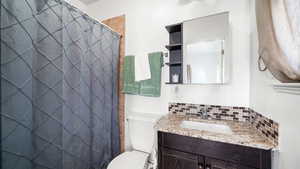 Bathroom with backsplash, curtained shower, and vanity