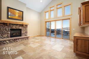Unfurnished living room featuring a stone fireplace, stone tile floors, recessed lighting, and high vaulted ceiling