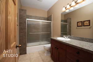 Full bath with vanity, shower / bath combination with glass door, and light tile patterned flooring