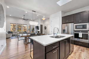 Kitchen with dark brown cabinets, open floor plan, appliances with stainless steel finishes, hanging light fixtures, and recessed lighting