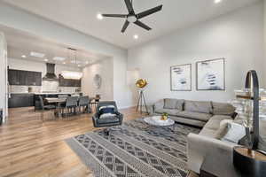 Living room with a chandelier, recessed lighting, light wood-style flooring, and a ceiling fan