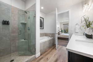 Full bathroom featuring ensuite bathroom, light wood-style floors, double vanity, a garden tub, and a shower stall