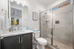 Bathroom with healthy amount of natural light, vanity, a stall shower, and a ceiling fan