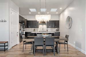 Dining area featuring a chandelier, light wood finished floors, a skylight, and recessed lighting