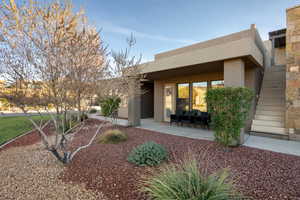 Back of house featuring stucco siding, stairway, and a patio
