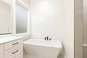 Bathroom with a freestanding tub, vanity, and light tile patterned floors
