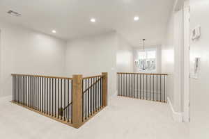 Hall featuring carpet floors, an upstairs landing, a chandelier, and recessed lighting