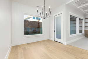 Unfurnished dining area with light wood-type flooring and a chandelier