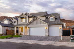 View of front facade featuring decorative driveway, brick siding, board and batten siding, a porch, and stucco siding