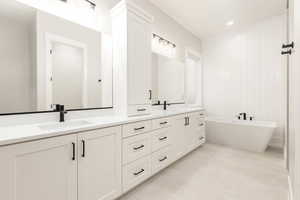Bathroom featuring double vanity, a freestanding tub, and light tile patterned flooring