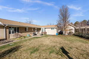 Rear view of house with a yard, a patio, and brick siding