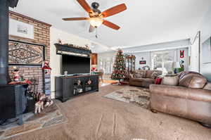Living room with a wood stove, carpet, and ceiling fan