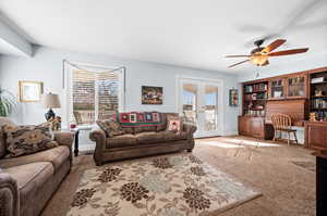 Living room featuring built in study area, a ceiling fan, carpet floors, and healthy amount of natural light