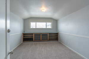 Bonus room featuring lofted ceiling, a textured ceiling, and light colored carpet