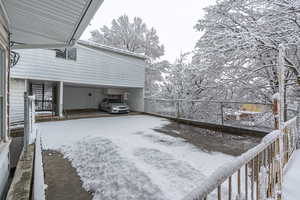Snow covered parking area with a carport