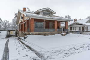 Bungalow featuring brick siding, a chimney, and covered porch
