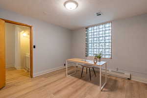 Office area with a textured ceiling, a baseboard radiator, and light wood-style floors