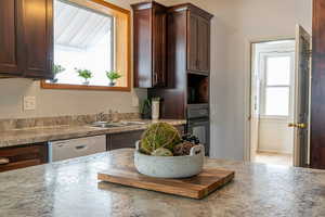 Kitchen featuring dark brown cabinets, oven, white dishwasher, and light countertops
