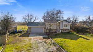 Bi-level home featuring driveway, a chimney, and an attached garage