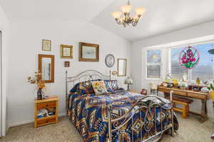 Bedroom with light colored carpet, vaulted ceiling, and a chandelier
