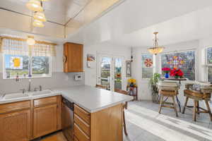 Kitchen with a breakfast bar, light countertops, a peninsula, and healthy amount of natural light