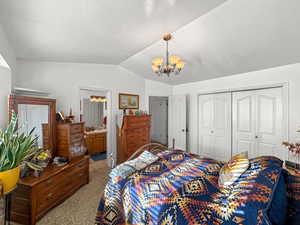 Bedroom with lofted ceiling, a chandelier, carpet flooring, a closet, and a textured ceiling