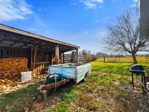 View of grassy yard featuring an outbuilding and a patio