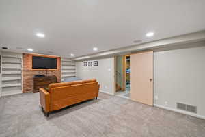 Living room with light colored carpet, built in shelves, recessed lighting, and stairway