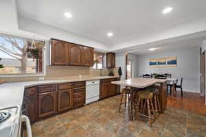 Kitchen featuring electric range, stone finish flooring, decorative backsplash, light countertops, and recessed lighting