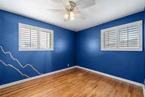 Unfurnished room with wood finished floors, a textured ceiling, plenty of natural light, and ceiling fan