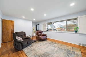 Living area with recessed lighting, wood finished floors, and crown molding