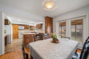 Dining area with healthy amount of natural light, light wood-style flooring, a textured ceiling, and recessed lighting