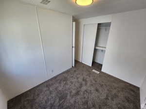 Unfurnished bedroom with dark colored carpet and a closet