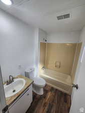 Bathroom with vanity, bathing tub / shower combination, dark wood finished floors, and a textured ceiling