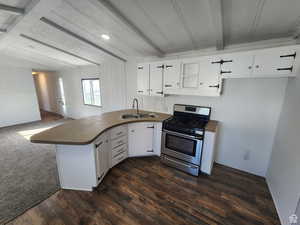 Kitchen featuring a peninsula, beam ceiling, gas stove, white cabinets, and open floor plan