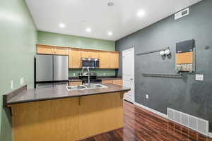 Kitchen with stainless steel appliances, a peninsula, dark wood-style flooring, recessed lighting, and light brown cabinetry