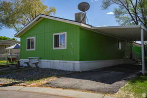 View of side of property with a carport and asphalt driveway