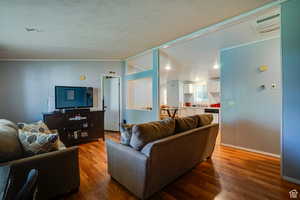 Living room featuring light wood-type flooring, cooling unit, vaulted ceiling, and a textured ceiling
