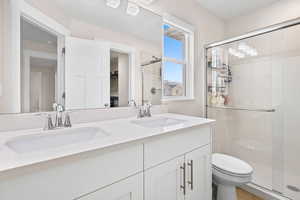 Bathroom with double vanity, a shower stall, a walk in closet, and tile patterned flooring