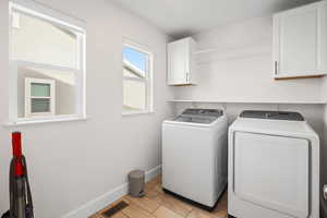 Washroom with separate washer and dryer, wood finish floors, and cabinet space