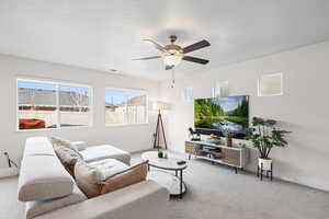 Carpeted living room with a ceiling fan and a textured ceiling