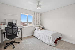 Carpeted bedroom with a desk and baseboards