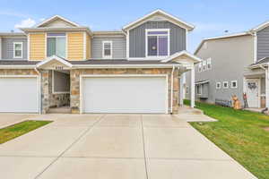 Craftsman-style home featuring stone siding, driveway, board and batten siding, a garage, and a front yard