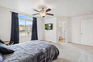 Bedroom featuring light carpet, ceiling fan, and ensuite bath